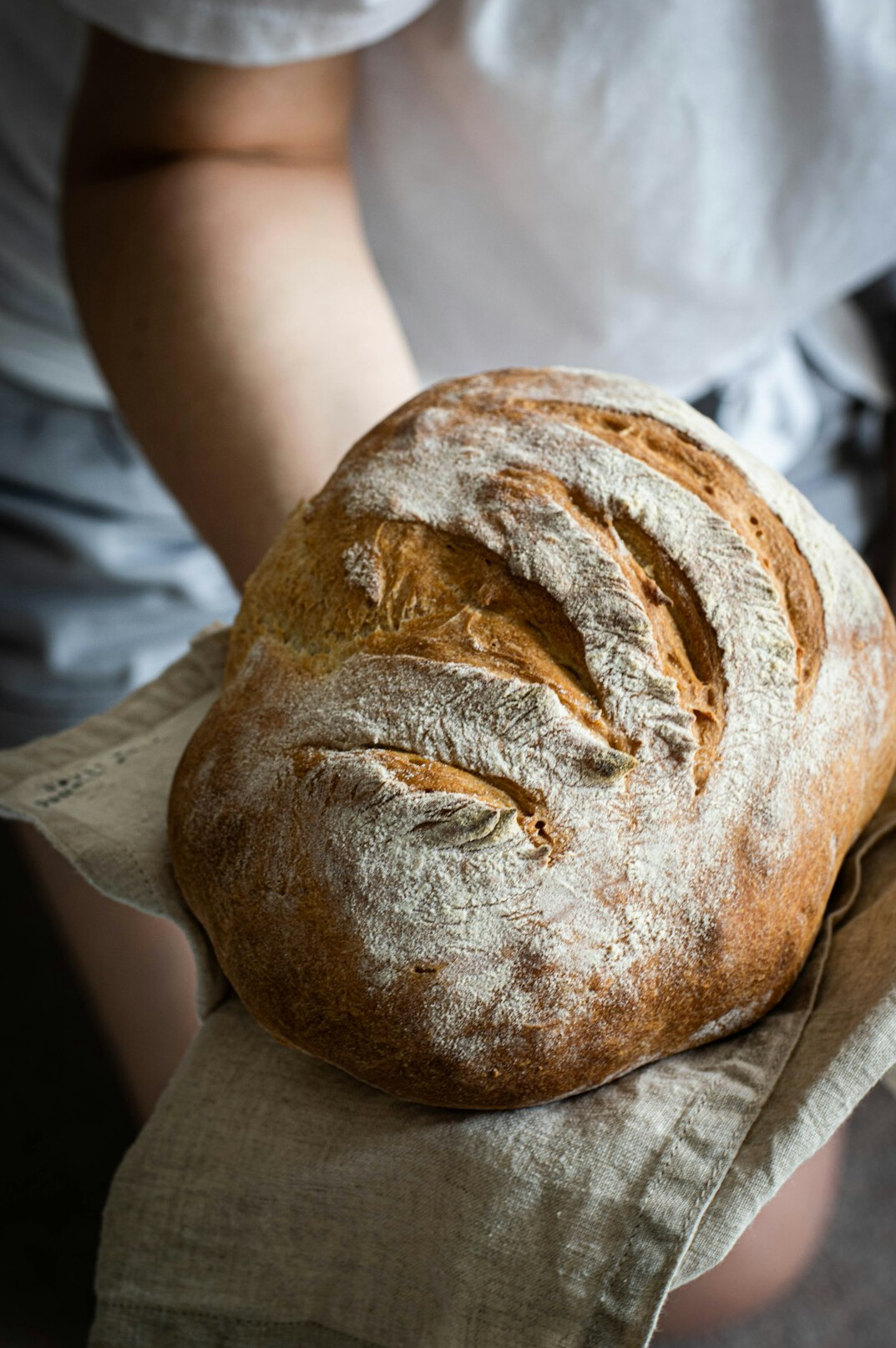 Danish baker holding fresh rye bread in a small bakery
